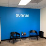 a white foam letter “sunrun” sign on a blue wall